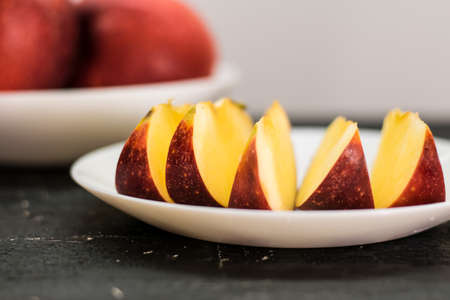 Sliced red apple on a white plate. Selective focus.の写真素材