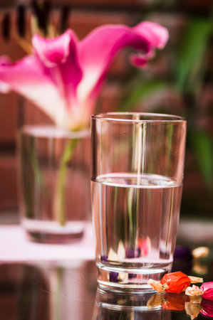 Glass of water and flowers on the table. Selective focus.
