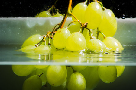 Green grapes in water. Water drops spray.