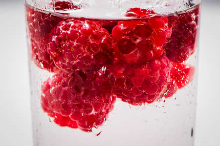 Fresh raspberries in a glass of water.の写真素材