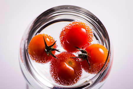 Fruit delicious cherry tomatoes in water. Water drops splashes.の写真素材