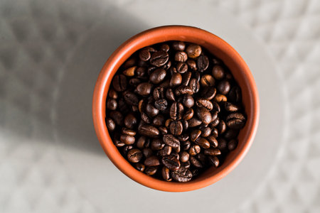 Mug with coffee beans, cinnamon and star anise. Isolated on black vintage background. The concept of...