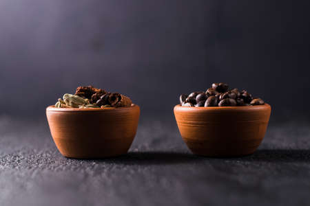 Mug with coffee beans, cinnamon and star anise. Isolated on black vintage background. The concept of aromas and spices, comfort and warmth. flat layの写真素材