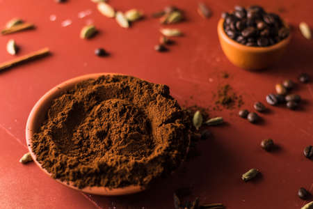 Coffee beans and ground coffee in a bowl on a red backgroundの写真素材