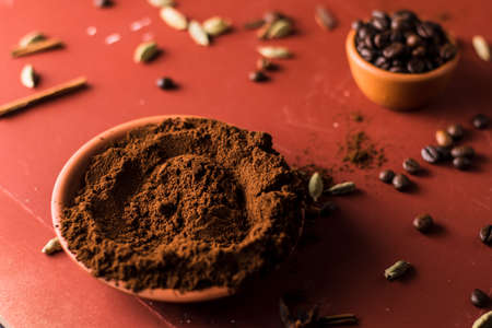 Coffee beans and ground coffee in a bowl on red backgroundの写真素材