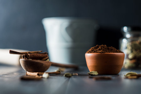cinnamon powder in a wooden bowl on a black background, selective focus