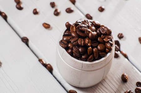 Coffee beans in a white cup on a white wooden backgroundの写真素材