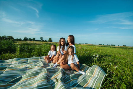 A mother and her children are playing and hugging in a field of flowers.の写真素材