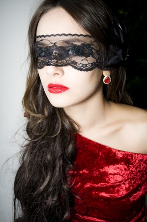 Lady in red dress with lace on a face の写真素材