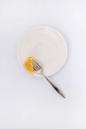Lemon on a white plate with a fork on a white backgroundの写真素材