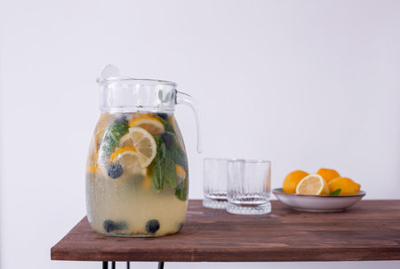 lemonade in glass and jug on wooden table outdoors. Summer refreshing drink. Cold detox water with lemonの写真素材