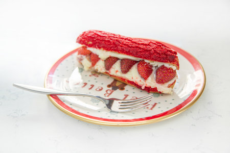 Fresh cake with strawberries on a red plate with a cup of cappuccino. Food and Christmas mood on a...