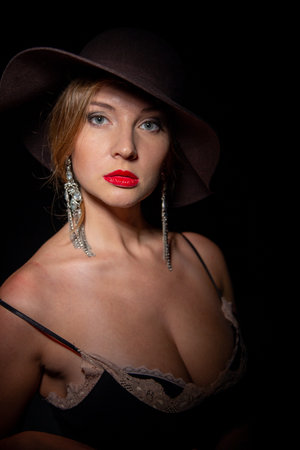 Sexy fashionable woman in an elegant hat and black dress. Mysterious blonde in retro style on a...