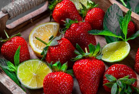 Strawberry fruit, mint leaves, lime and lemon halves on a vintage wooden tray. Mojito mix on the rustic wooden salverの写真素材