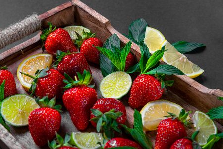 Strawberry fruit, mint leaves, lime and lemon halves on a vintage wooden tray. Mojito mix on the rustic wooden salverの写真素材