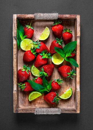 Strawberry fruit, mint leaves, lime and lemon halves on a vintage wooden tray. Mojito or lemonade mix on the rustic wooden salverの写真素材
