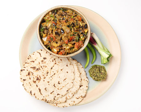 roasted egg plant and bhakri or Indian flat bread served with green chilli chutney traditionally called as Theccha in Marathi and spring onion beside the plate.の写真素材