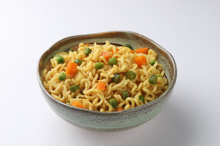 Noodles with green peas and carrots in bowl on white backgroundの写真素材