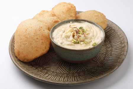 Shrikhand & Puri  Shrikhand is an Indian sweet dish made of strained curd garnished with dry fruits and saffron. Served in a ceramic bowl  plate with Puri Deep fried flat breadの写真素材