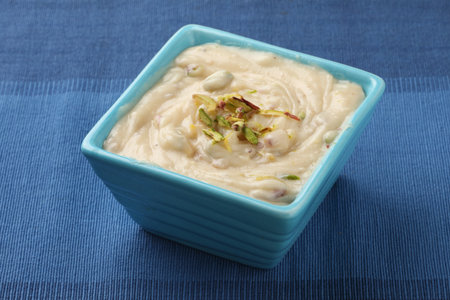 Shrikhand is an Indian sweet dish made of strained curd,garnished with dry fruits and saffron. Served in a ceramic bowl.Selective focusの写真素材