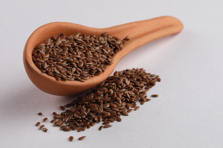 Flax seeds in terracotta spoon on white background. Healthy food.の写真素材
