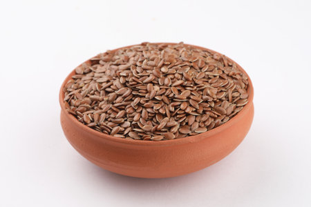 Flax seeds in a clay bowl on a white background, isolatedの写真素材