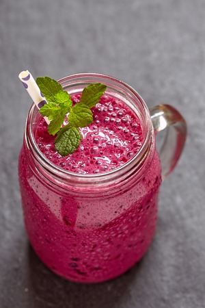 Blueberry smoothie in a mason jar with a straw and sprig of mintの写真素材