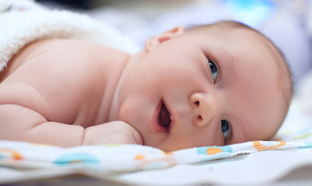 Adorable beautiful newborn baby boy looking upの写真素材