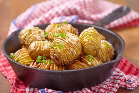 Baked hasselback potatoes with cheese and green onionの写真素材