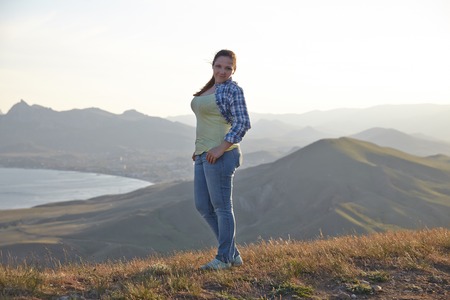 Woman traveler looks at the edge of the cliff on the  sea bay of mountains in the backgroundの写真素材