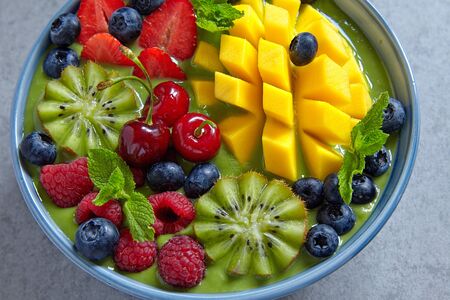 breakfast green smoothie bowl topped with fruits and berries