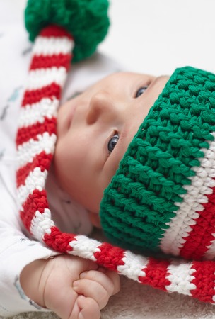 Newborn baby wearing a knitted Christmas elf hat.の写真素材