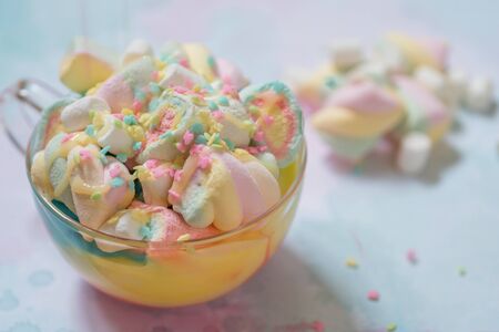 Rainbow hot chocolate with colorful marshmallow on a tableの写真素材