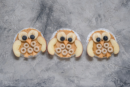 Funny owl with peanut butter, cereal and fruits banana apple on rice cake for kids breakfastの写真素材