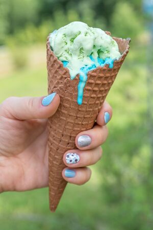 hand holding an green and blue ice cream cone