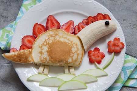 Funny dinosaur shaped pancake with strawberry, banana and chocolateの写真素材