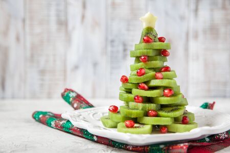 Healthy dessert idea for kids party - funny edible kiwi pomegranate Christmas treeの写真素材