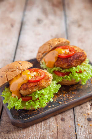 chicken burgers with vegetables on a wooden tableの写真素材