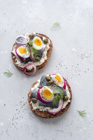 Smorrebrod with herring, onion and eggs on whiteの写真素材