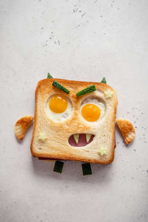 Fun Halloween monster sandwich with slice meat sausage, eggs and cheese on plateの写真素材