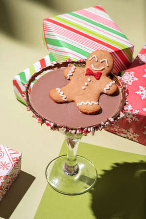 Gingerbread cookie man in a Christmas cocktail with christmas presents