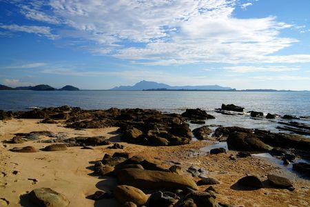 The blue sea of the stony coast which have grown with jungle of peninsula Santubong. Borneo.の写真素材
