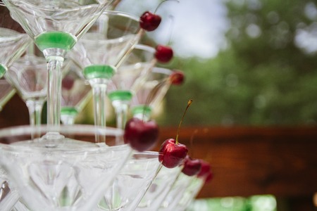 Closeup of martini glasses arranged in the shape of a pyramid, standing on each other with cherry insideの写真素材