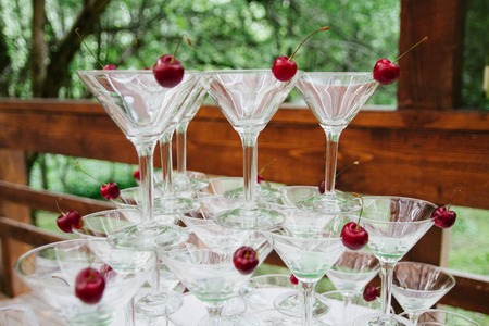 Closeup of martini glasses arranged in the shape of a pyramid, standing on each other with cherry insideの写真素材
