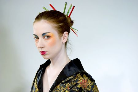 Attractive young woman wearing elaborate makeup with chopsticks in her hair bunの写真素材