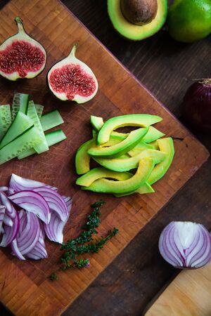 figs, avocado, cucumber, arugula, red onion, thyme on a cutting wooden board close-up - salad...
