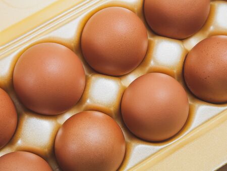 brown large chicken eggs in yellow packaging close-upの写真素材