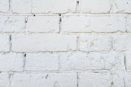 Old cracked brick wall painted in white paint close-up