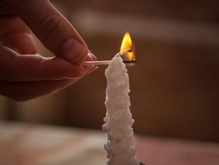 man lights a candle with a matchの写真素材