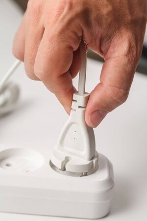 plug in a white extension cord, male hand closeupの写真素材